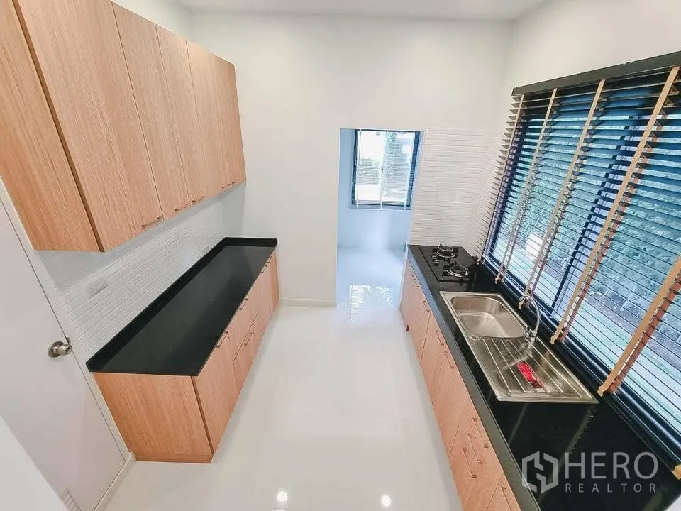 独栋房屋 for rent or sale in Bang Phli, Samut Prakan - 独立厨房，黑色长台面，水槽、燃气灶与木柜体。