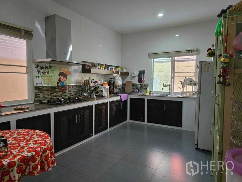 Land for sale - Large Thai-style kitchen with dark built-in cabinets, gas hob, and two windows.