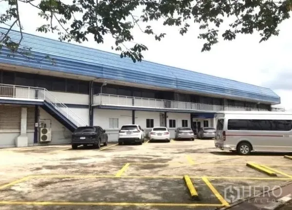 Factory for rent in Bang Bua Thong, Nonthaburi - Two-storey factory block with parking bays and exterior staircase.