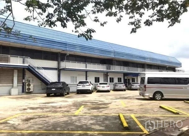 Factory for rent in Bang Bua Thong, Nonthaburi - Two-storey factory block with parking bays and exterior staircase.