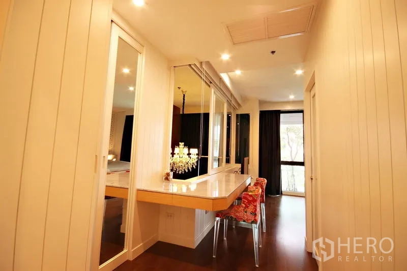 Condominium for rent or sale in Khlong Toei, Bangkok - Dressing area with mirrored wardrobe, chandelier lamp, and built-in vanity.