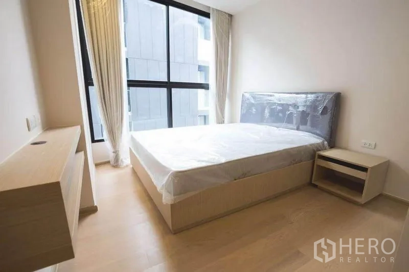 公寓 出租在Watthana, Bangkok - 主卧，大窗、双人床与床头柜。