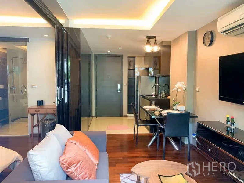 คอนโด ให้เช่าในWatthana, Bangkok - มุมมองจากโซฟาไปยังประตูทางเข้า เห็นครัวบิวท์อิน โต๊ะทานอาหาร และฉากกั้นกระจกห้องน้ำ