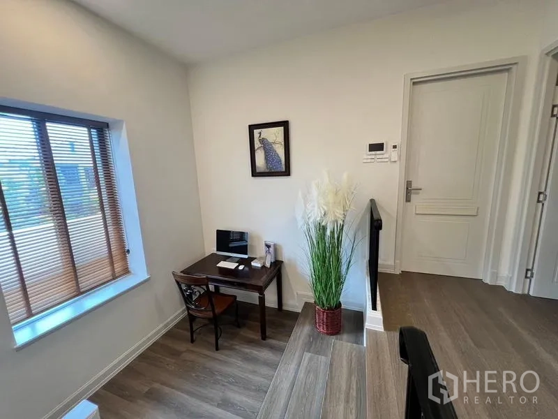 Detached House for rent or sale in Saphan Sung, Bangkok - Study nook by the stair landing with desk, window and wall art.