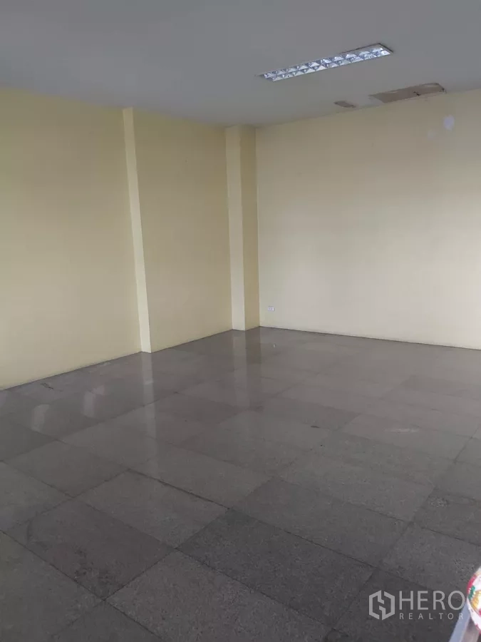 Warehouse for rent in Krathum Baen, Samut Sakhon - Empty multipurpose room with grey granite tiles and cream walls.
