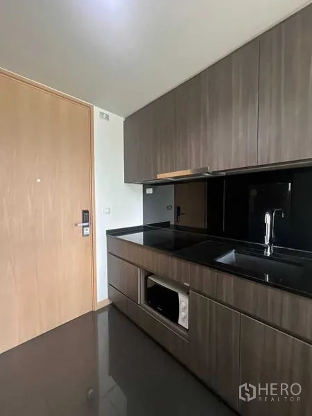 公寓 出租或出售在Watthana, Bangkok - 紧凑厨房，黑色石材台面，内置橱柜与家电。