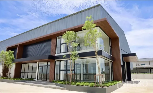 Factory for rent or sale in Phutthamonthon, Nakhon Pathom - Close view of the double-height entrance and corner glazing with landscaped planters.