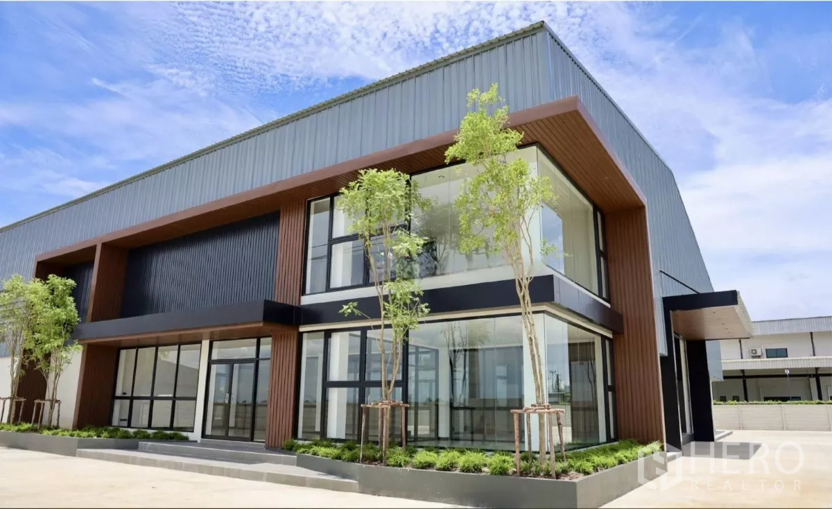 Factory for rent or sale in Phutthamonthon, Nakhon Pathom - Close view of the double-height entrance and corner glazing with landscaped planters.