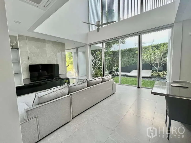 Detached House for rent or sale in Bang Phli, Samut Prakan - Open-plan living area with sliding glass doors leading to a lawned garden.
