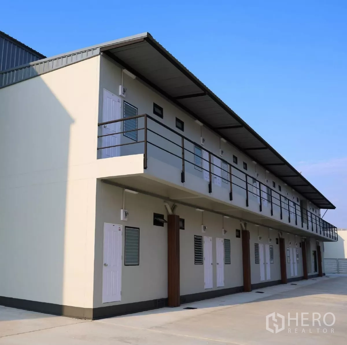 Factory for rent or sale in Phutthamonthon, Nakhon Pathom - Two-storey staff housing block with balcony corridor and multiple room entrances.