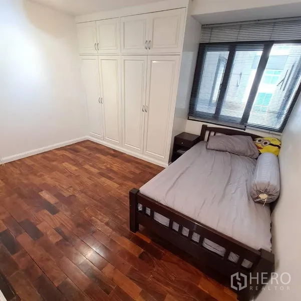 Condominium for rent or sale in Watthana, Bangkok - Secondary bedroom with single bed, built-in wardrobes, window blinds and wooden flooring.