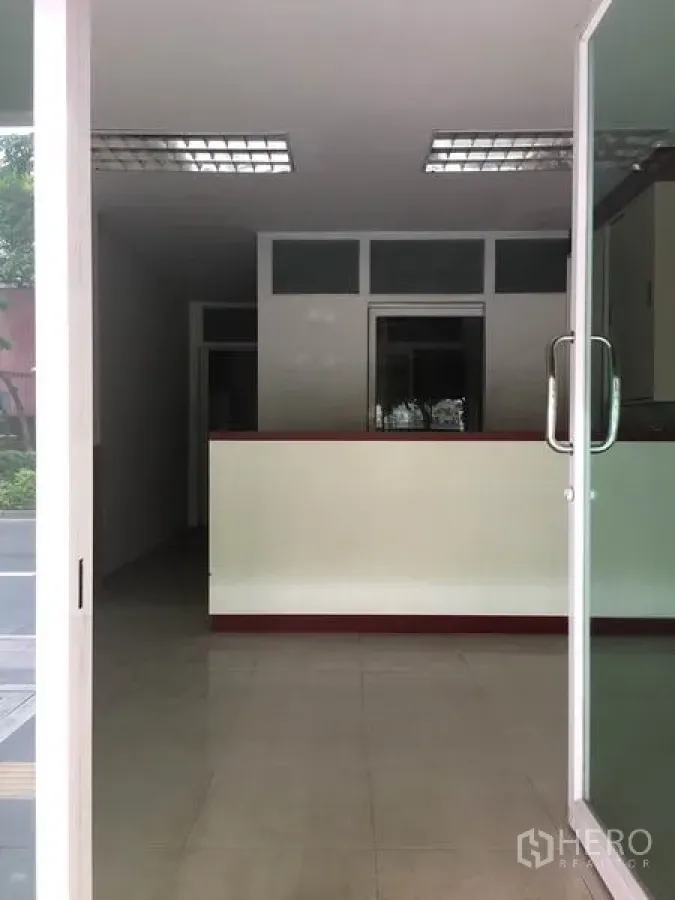 Shophouse for rent in Khlong Toei, Bangkok - Glass door entrance opening to a reception counter and tiled lobby.