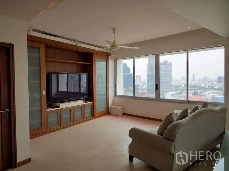 Condominium for rent in Khlong San, Bangkok - Living room with custom wood media wall and city views through wide windows.