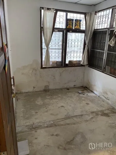 Townhouse for rent in Lat Phrao, Bangkok - Upper bedroom with bare concrete floor and corner windows, ready for renovation.