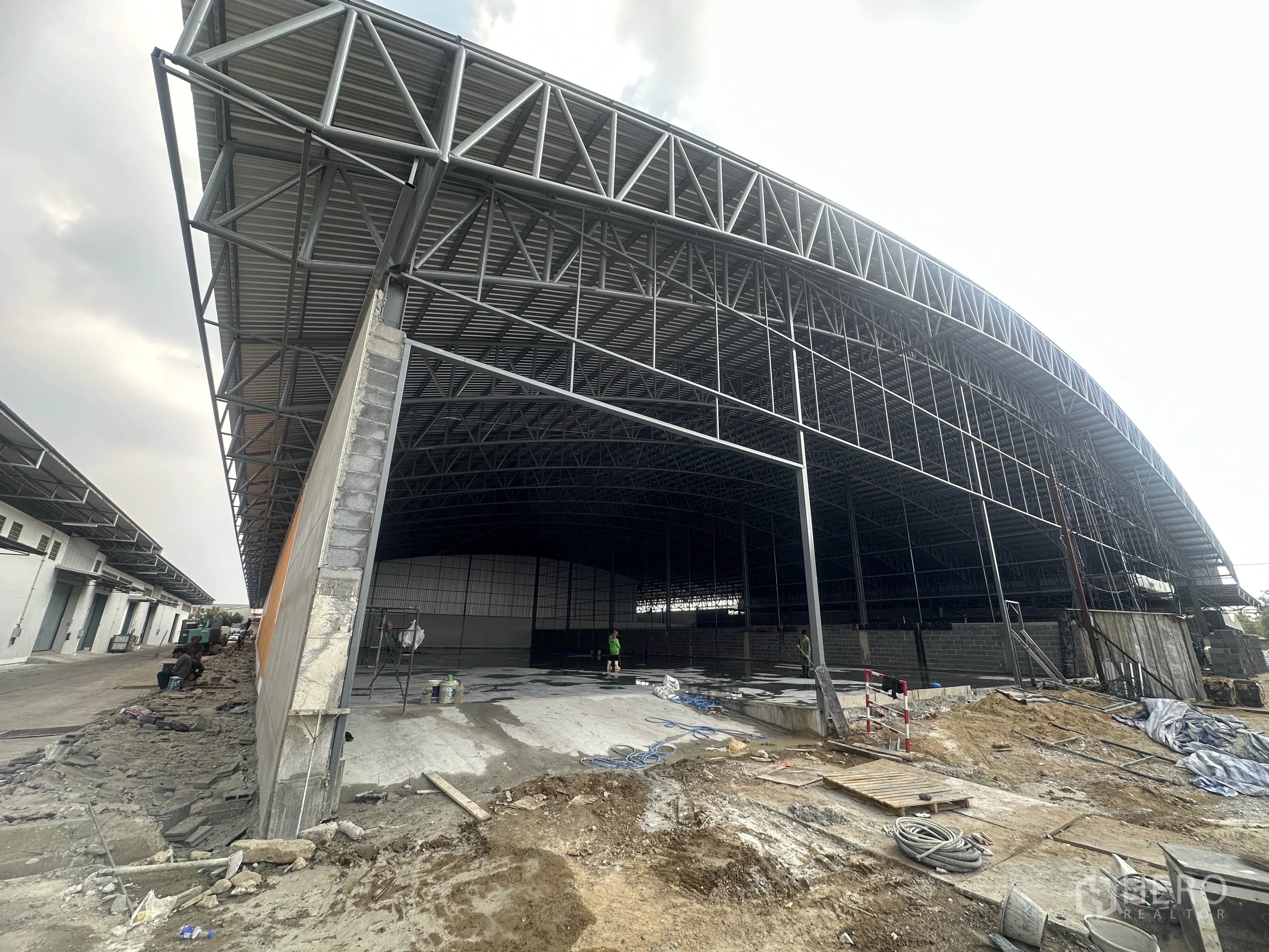 Warehouse for rent in Pak Kret, Nonthaburi - Large warehouse bay with robust steel structure, high roof and concrete floor being prepared.