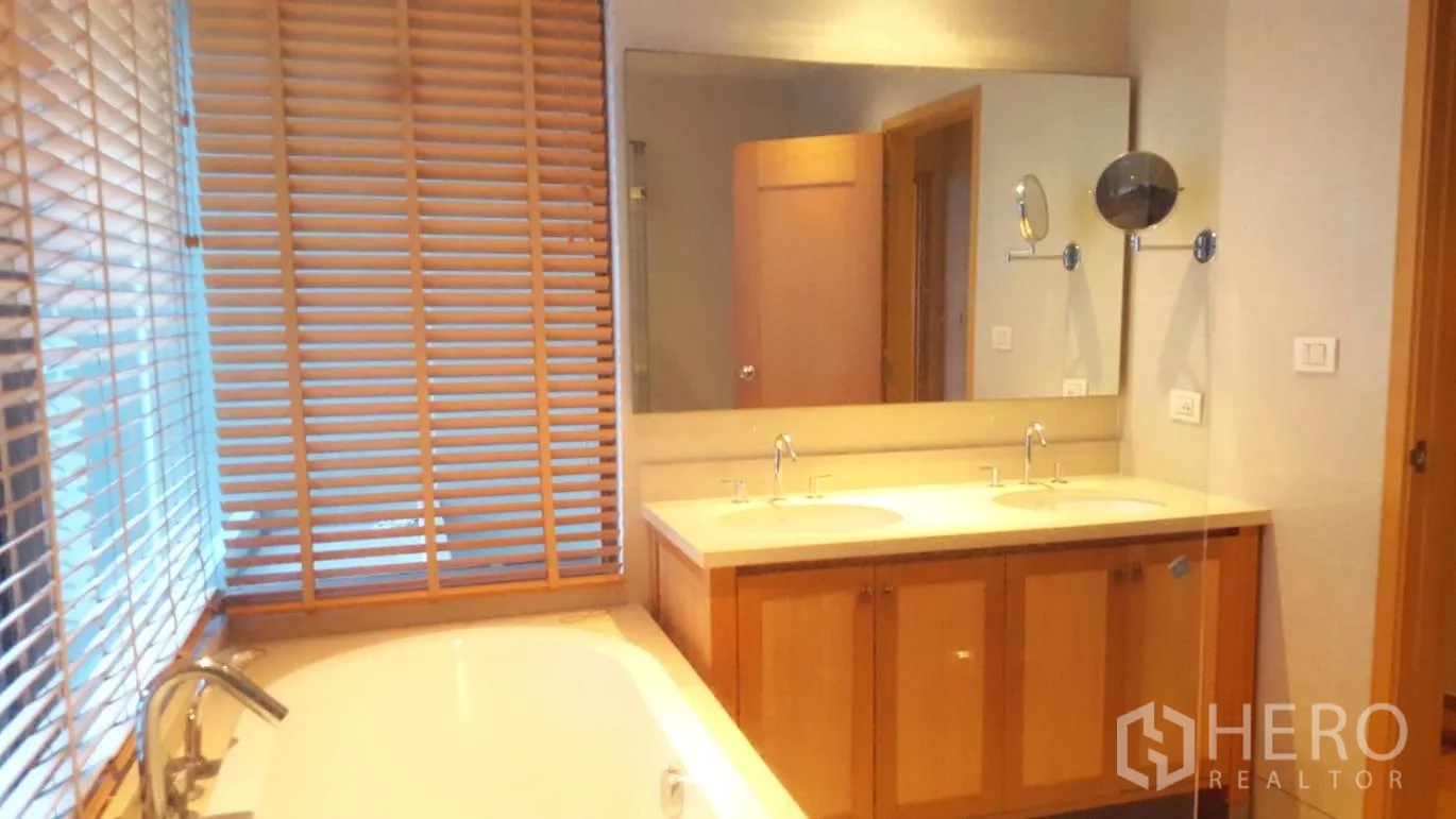 Condominium for rent or sale in Khlong Toei, Bangkok - Bathroom featuring a bathtub by the window, double vanity and large mirror.