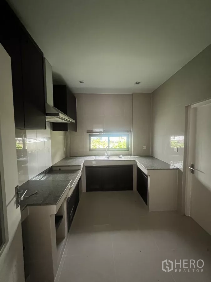 Detached House for sale in Bang Kapi, Bangkok - Separate Thai kitchen with U-shaped counters, range hood, and a window above the sink.