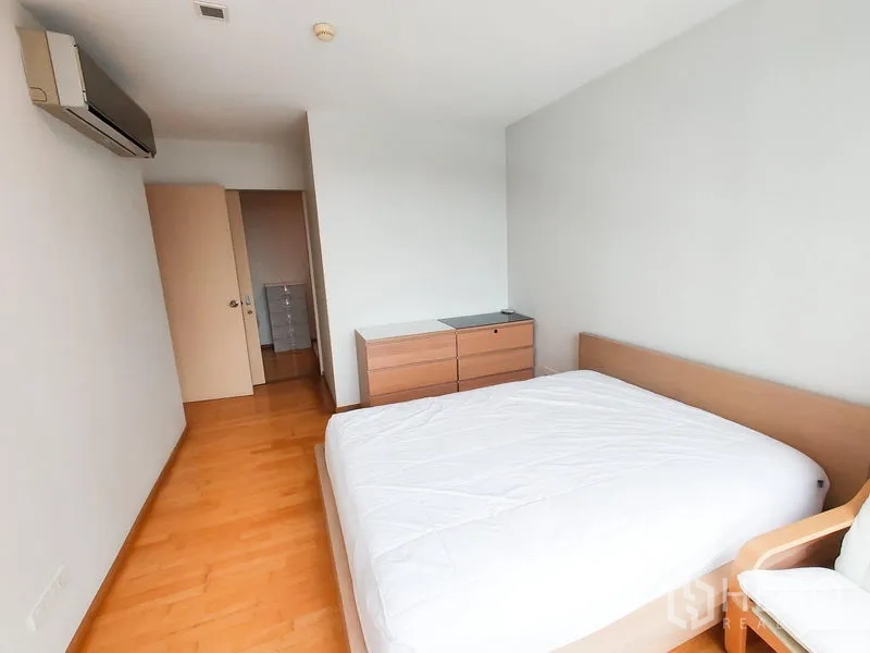 Condominium for rent in Khlong Toei, Bangkok - Second bedroom with double bed, dresser and air conditioning on warm wood flooring.