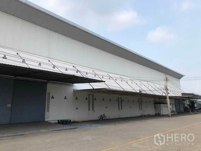 Factory for rent in Bang Bua Thong, Nonthaburi - Side elevation of the warehouse showing continuous awning, vents, and clear truck access.