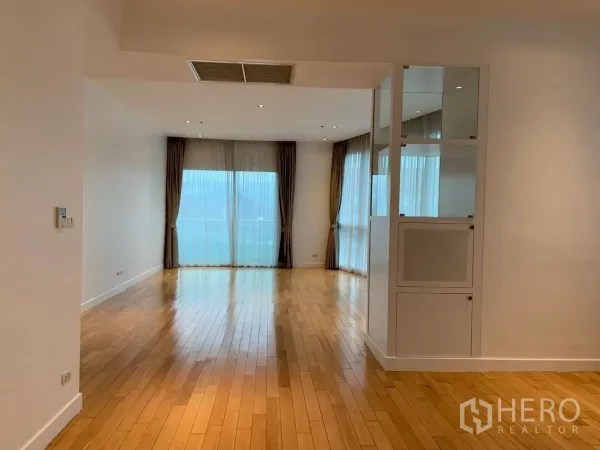 Condominium for rent in Khlong Toei, Bangkok - Long open living–dining space with wood floors leading to a balcony.