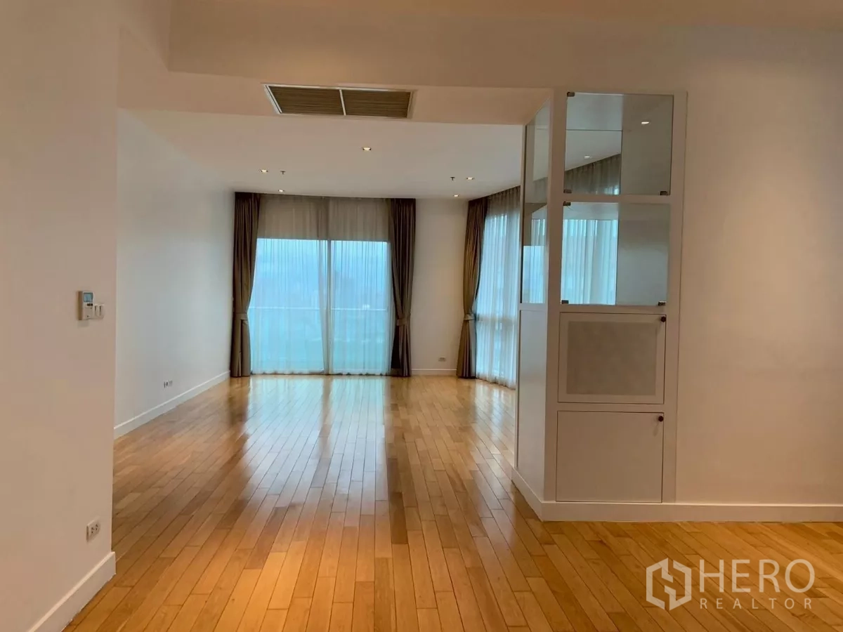 Condominium for rent in Khlong Toei, Bangkok - Long open living–dining space with wood floors leading to a balcony.