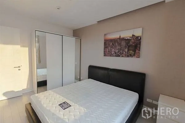 Condominium for rent in Huai Khwang, Bangkok - Master bedroom with king bed and sliding-door wardrobe, daytime light.