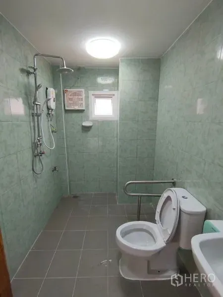 Detached House for rent in Khlong Toei, Bangkok - Green-tiled bathroom featuring a walk-in shower, water heater and toilet with grab bar.