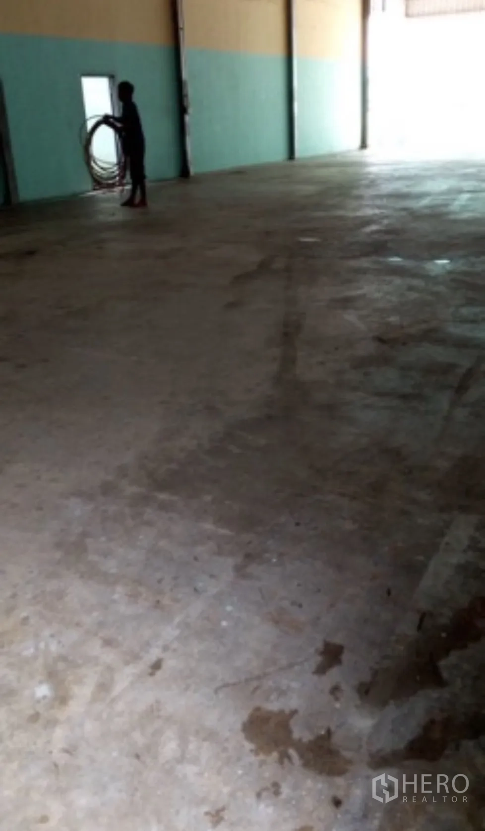 Warehouse for rent in Pak Kret, Nonthaburi - Concrete warehouse floor inside near a large opening.