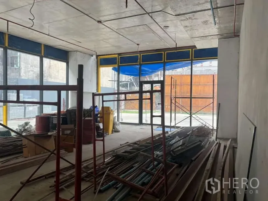 零售空间 出租 - 毛坯零售空间，层高通透，整面落地玻璃门面，室内有脚手架与建材。