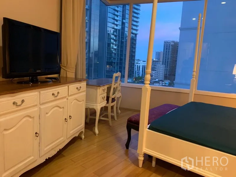 คอนโด ให้เช่าในWatthana, Bangkok - ห้องนอนมาสเตอร์เตียงสี่เสา ตู้ทีวี โต๊ะทำงาน และวิวสกายไลน์เมืองผ่านหน้าต่าง