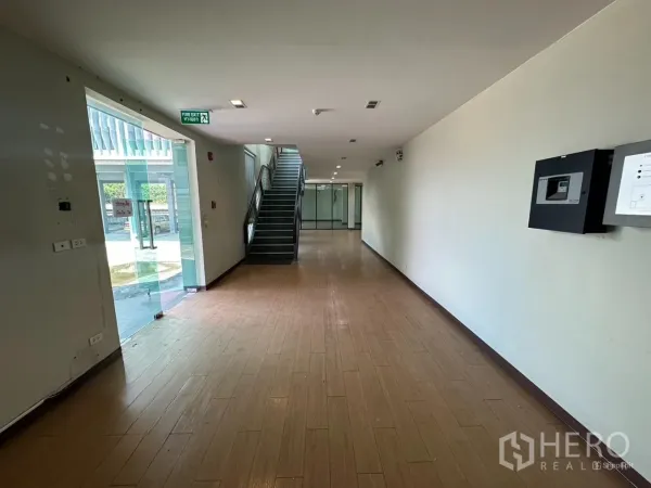 带办公室的家 出租在Prawet, Bangkok - 一层走廊，木纹地面、玻璃入口与楼梯。