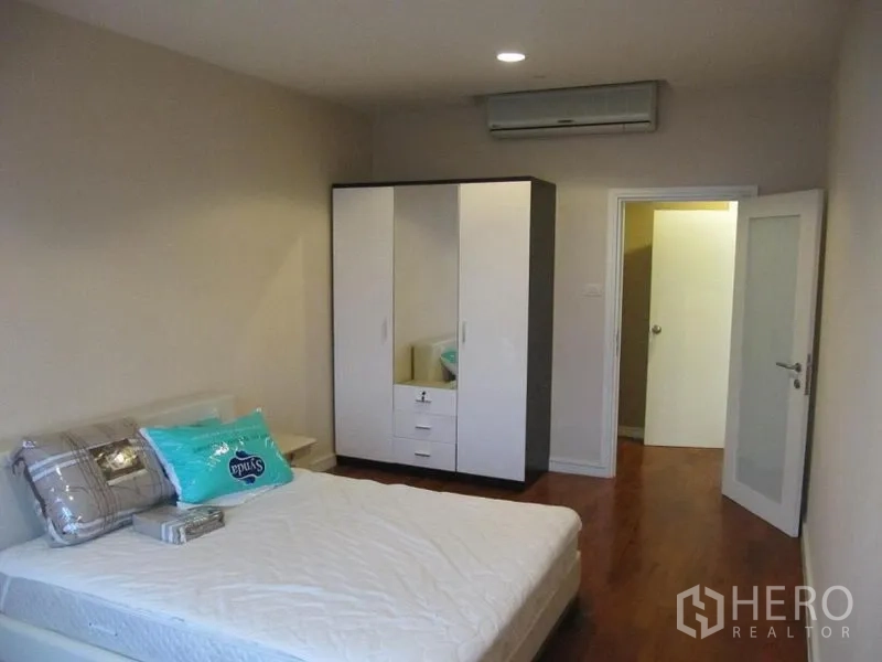 Condominium for rent in Khlong Toei, Bangkok - Second bedroom with double bed, wardrobe storage, air conditioning, and doorway to bathroom.