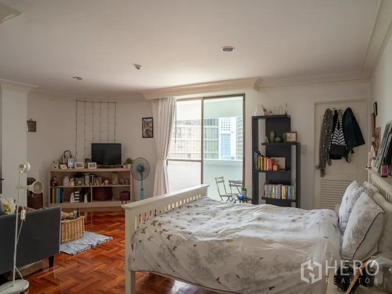 อพาร์ทเมนท์ for rent in Khlong Toei, Bangkok - ห้องนอนสว่างพร้อมประตูเชื่อมระเบียง ชั้นวางของ และพื้นไม้.