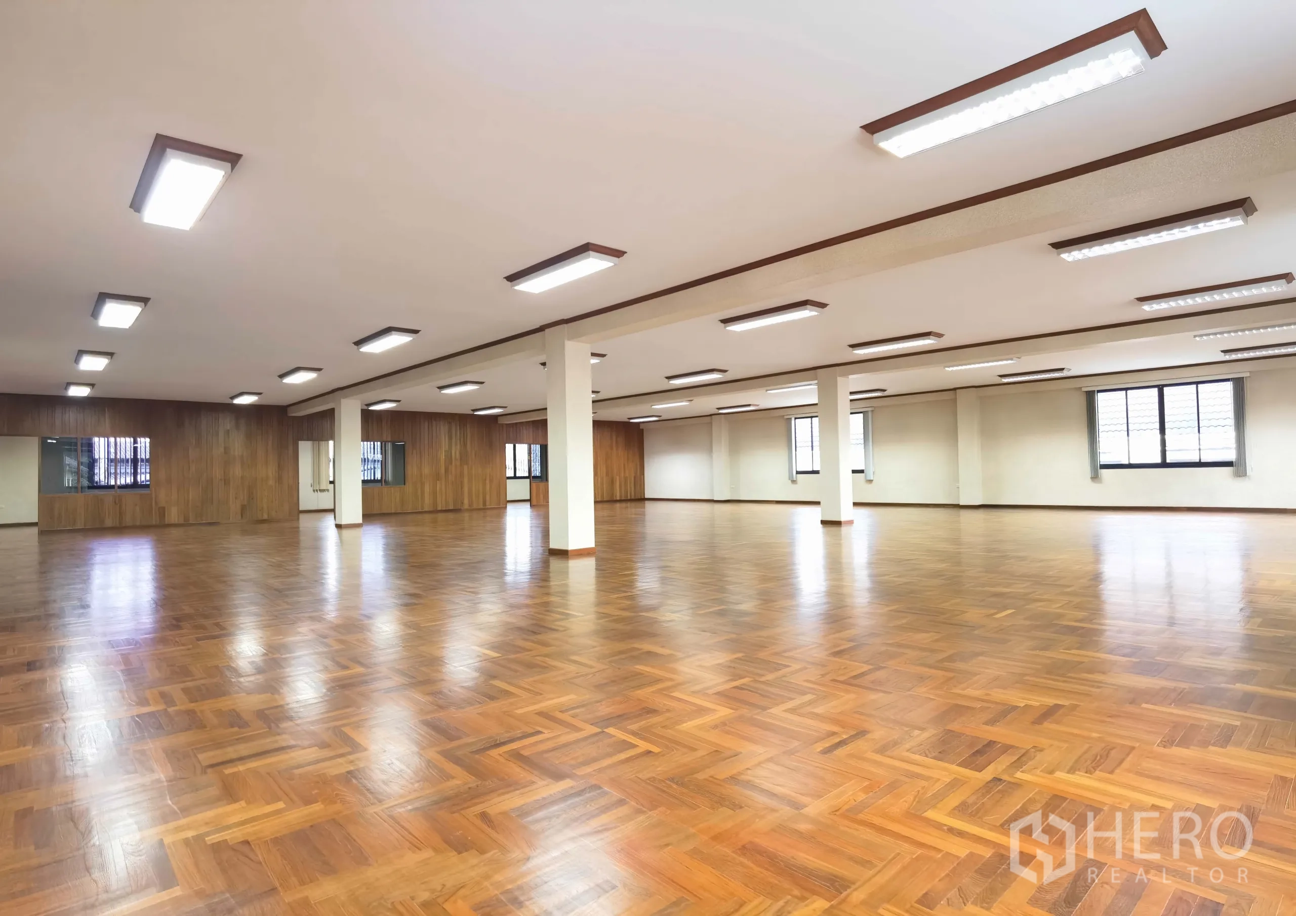 Warehouse for rent in Samut Prakan - Open multi‑purpose room with wood floors and pillars, suitable for training or large office space.