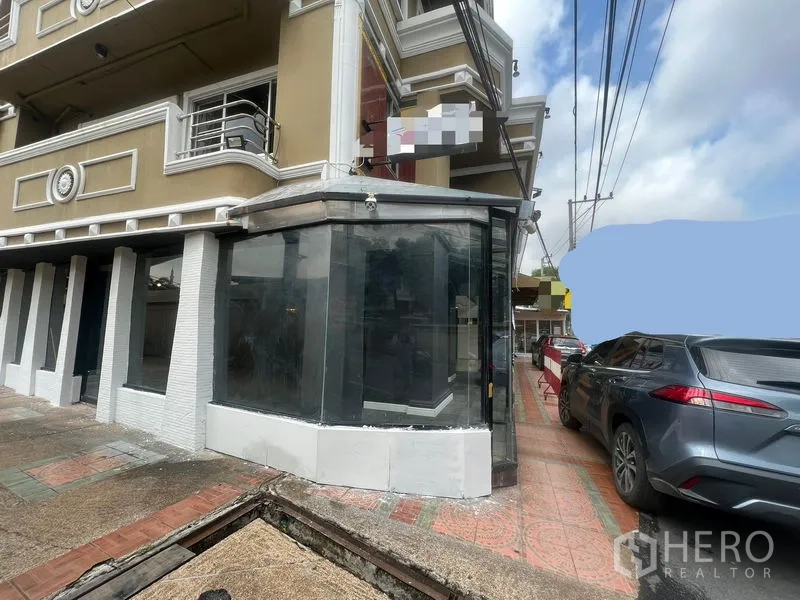 Retail Space for rent in Watthana, Bangkok - Corner retail unit exterior with wraparound display windows beside a parking area.