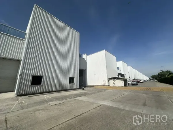 Factory for rent in Khlong Luang, Pathum Thani - Twelve-meter-wide access road lined with white factory buildings and loading bays.