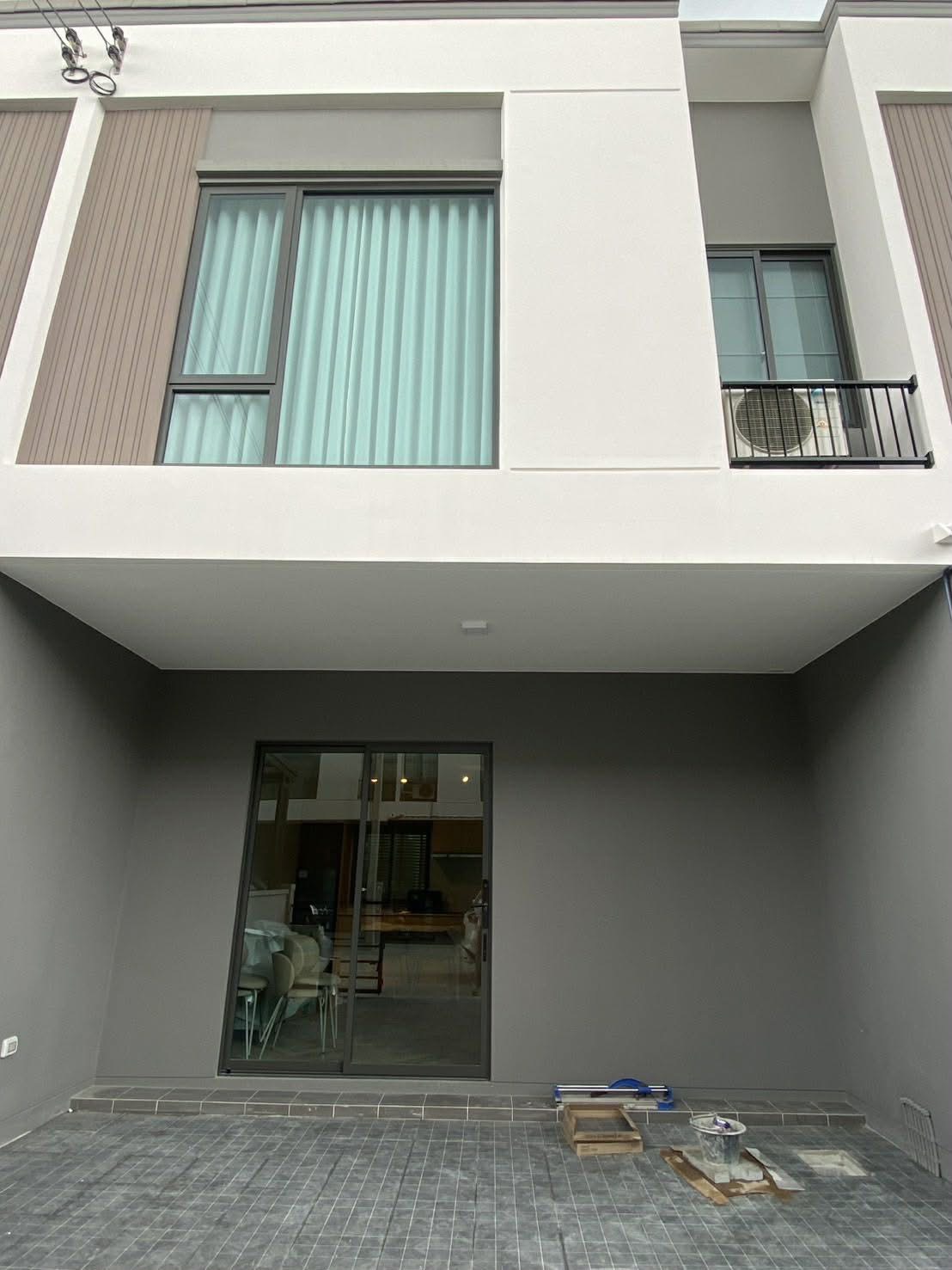 Townhouse for rent in Bang Phli, Samut Prakan - Contemporary townhouse facade with upper windows and a covered carport with sliding door.