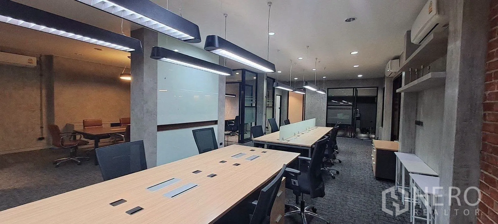 Home Office for rent in Lat Phrao, Bangkok - Open-plan desks with brick wall accents and overhead linear lights.