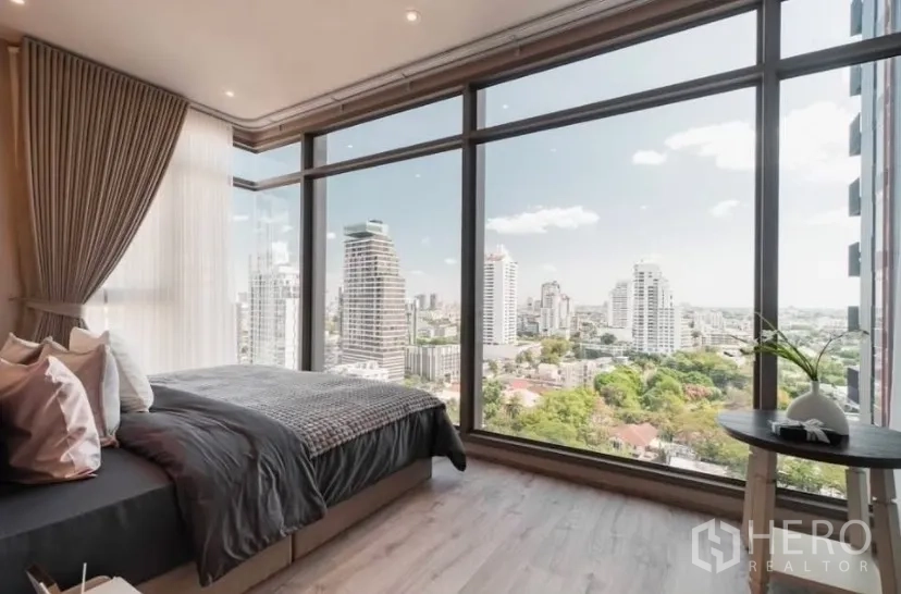 Condominium for rent in Watthana, Bangkok - Corner bedroom with floor-to-ceiling windows and panoramic Bangkok skyline view.