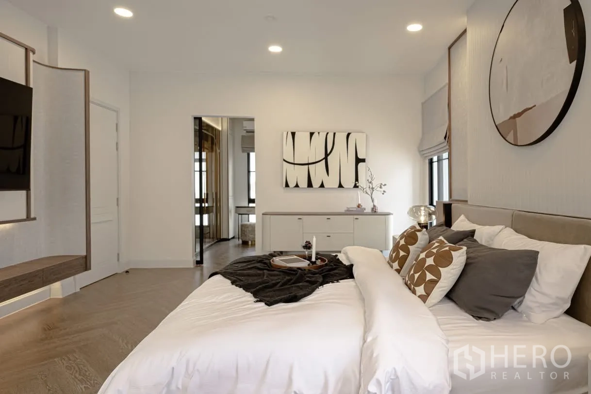 Detached House for rent in Saphan Sung, Bangkok - Serene master bedroom with king bed, wall-mounted TV, wood flooring, and modern art.