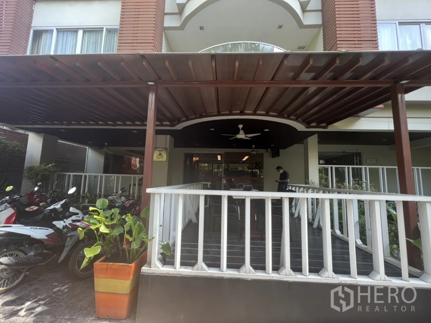 零售空间 出租在Khlong Toei, Bangkok - 入口露台，宽檐雨棚与白色栏杆，可眺望车道的座位区。