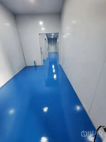 工厂 出租在Lam Luk Ka, Pathum Thani - 洁净走廊，亮面环氧地坪与白色面板墙，通往工作间。