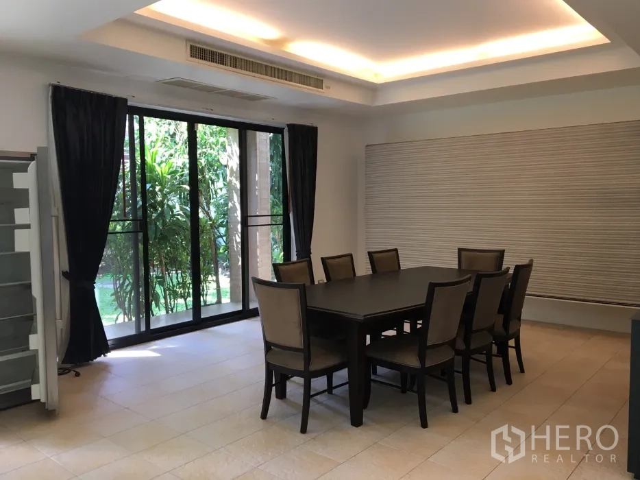 บ้าน ให้เช่าในWatthana, Bangkok - ห้องรับประทานอาหารพร้อมโต๊ะ 8 ที่นั่ง ไฟฝ้าซ่อนไฟ และผนังกระจกมองเห็นสวน.