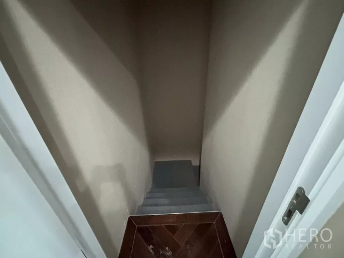Condominium for sale in Bang Kho Laem, Bangkok - Narrow internal staircase leading down from a mezzanine with a small wood landing.