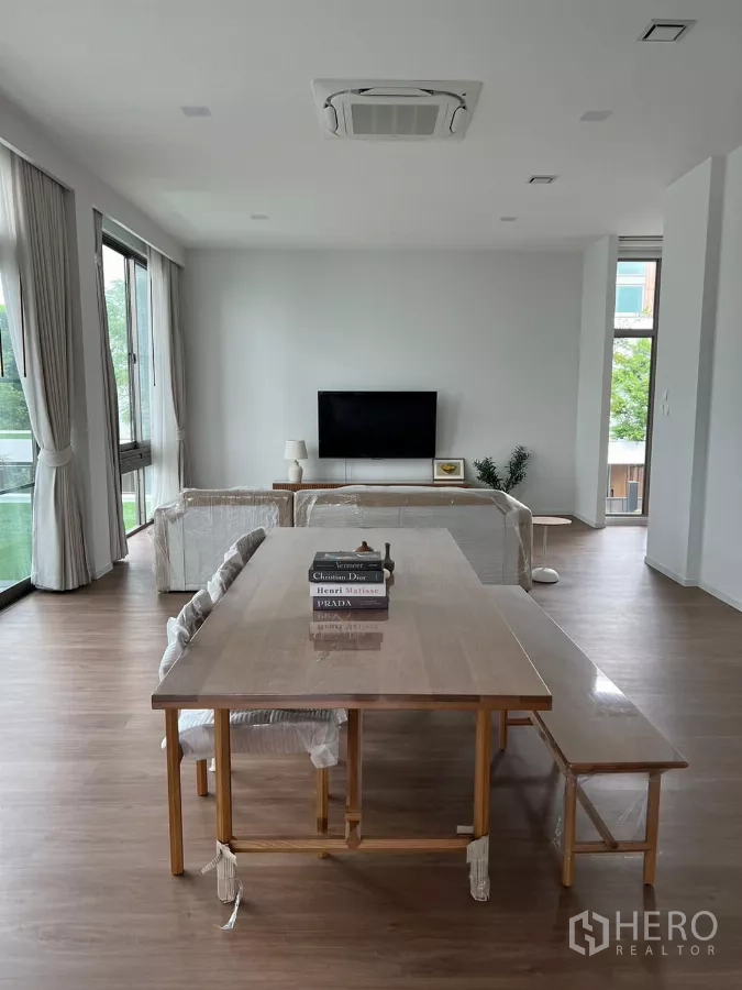Detached House for rent in Saphan Sung, Bangkok - Open-plan dining and living area with a long table, ceiling cassette aircon and TV.