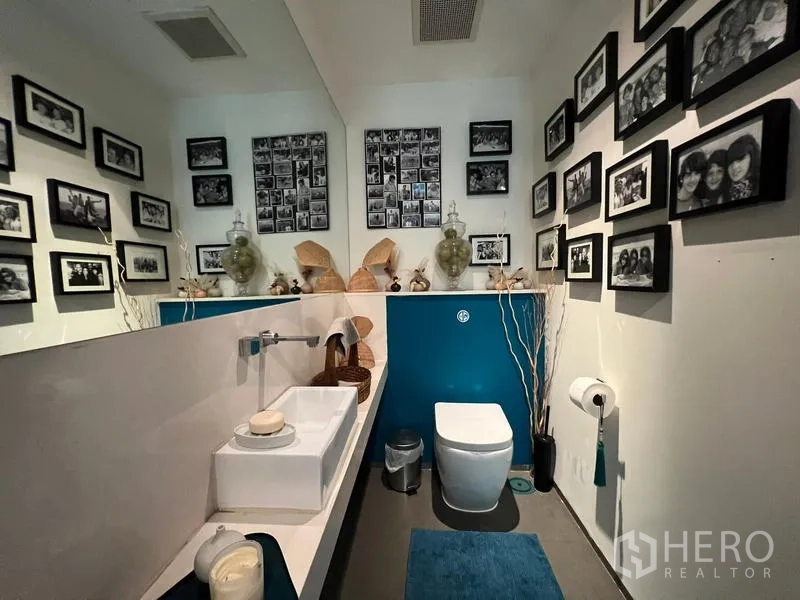 Condominium for sale in Khlong San, Bangkok - Stylish powder room with blue accent wall and a gallery of framed photos.