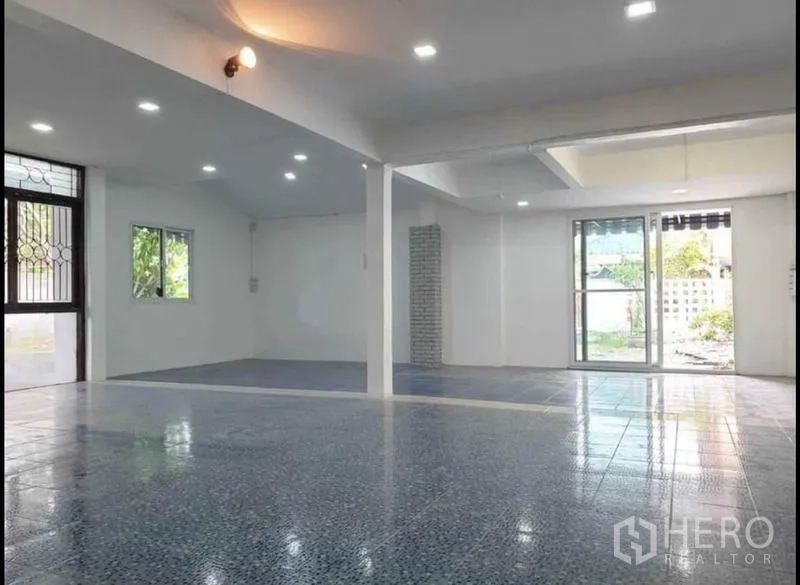 独立式住宅 出租在Lat Phrao, Bangkok - 大面积开放大厅，LED筒灯、花纹地砖与通往花园的推拉门。