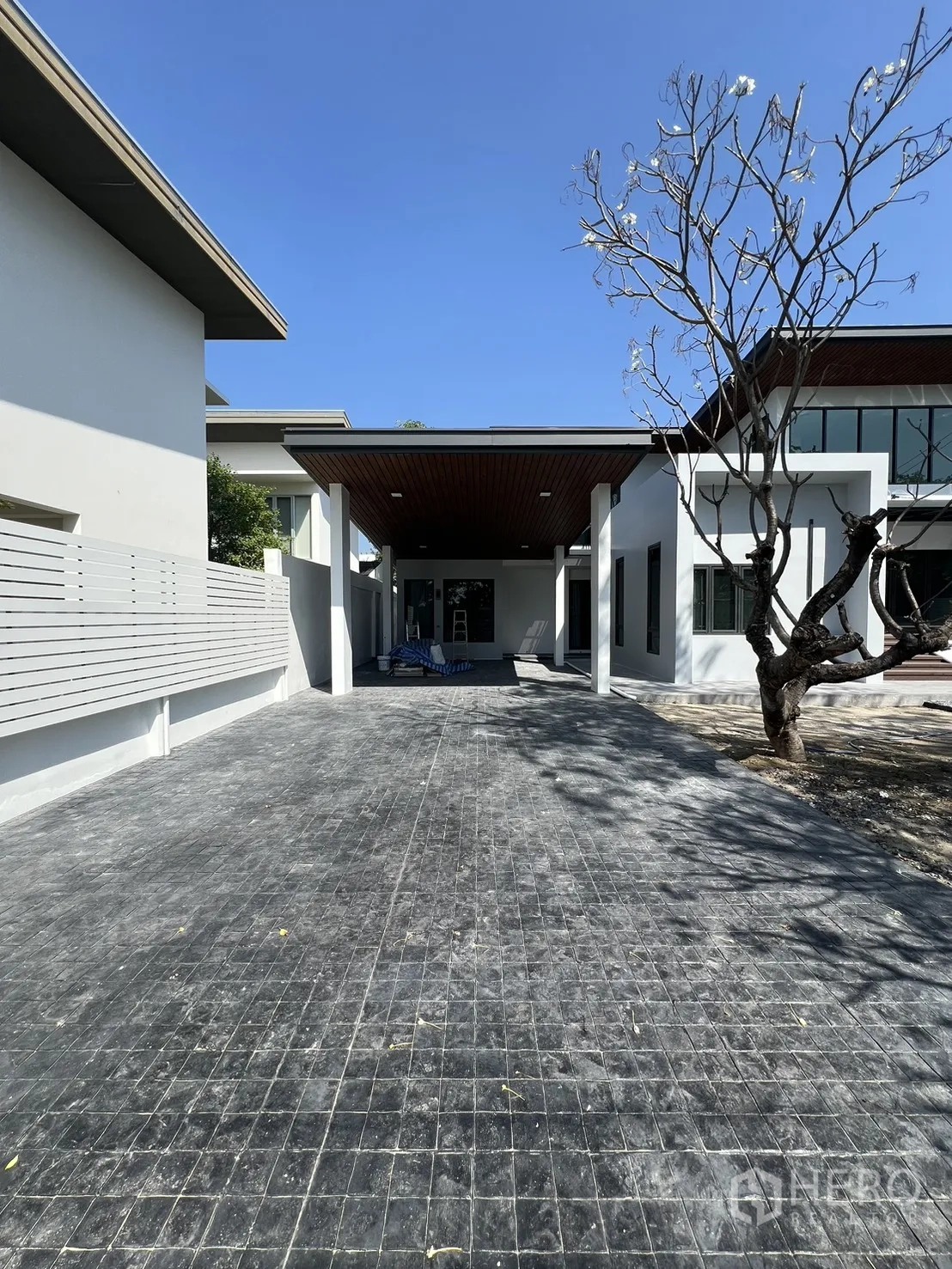 Detached House for rent in Saphan Sung, Bangkok - Covered carport and long driveway beside a frangipani tree.