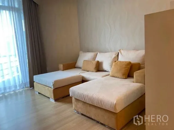 公寓 出租在Khlong San, Bangkok - 客厅配L型沙发，落地纱帘旁采光充足。