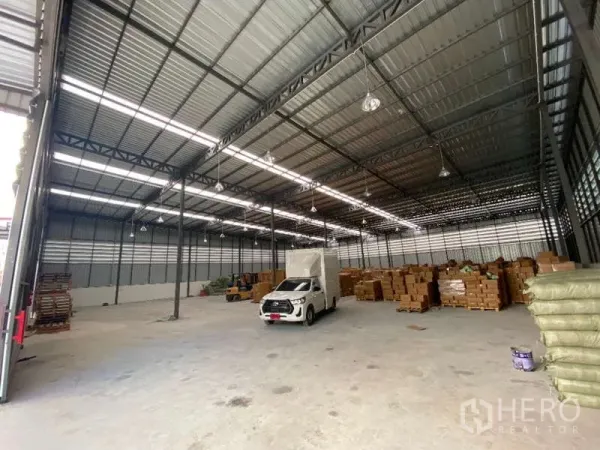 货栈 出租在Don Mueang, Bangkok - 仓库内部高跨空间，钢桁架屋顶与照明，可见小型货车与堆放货物。